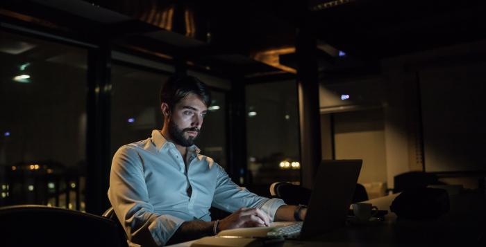 Businessman in office at night typing on laptop