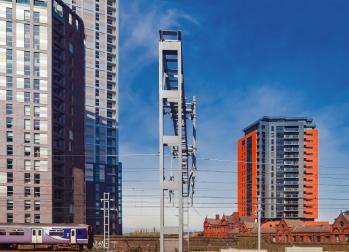 A trains passes between buildings in Manchester