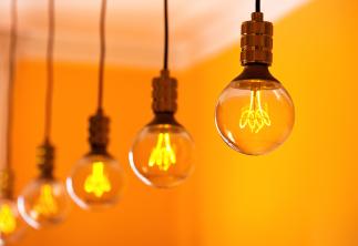 A row of exposed lightbulbs with an orange wall in the background