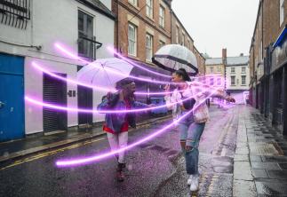 Two women dancing in the rain with umbrellas and glowlines