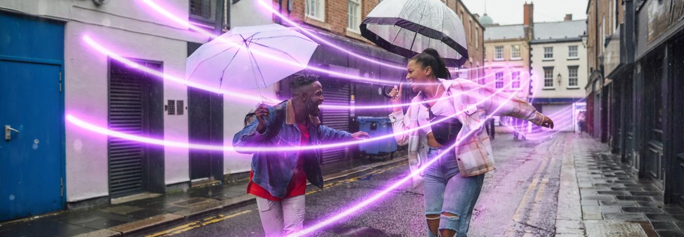 Two women dancing in the rain with umbrellas and glowlines