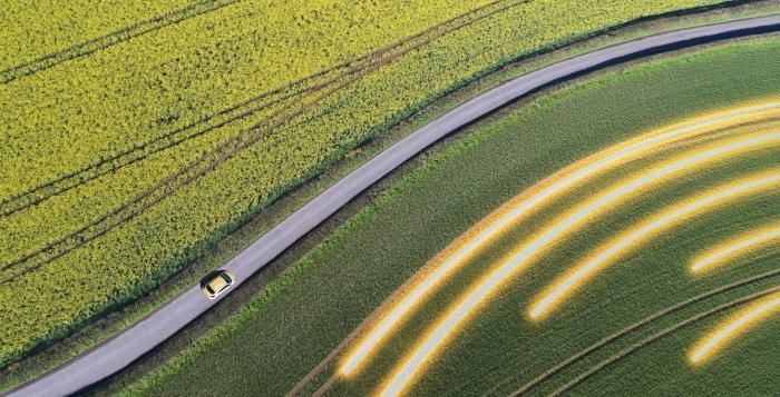 Aerial view of car driving on country road between fields