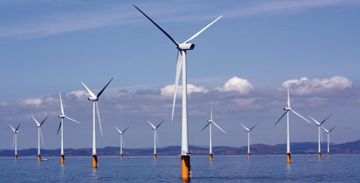 A seascape underneath a blue sky with wind turbines appearing out of the water