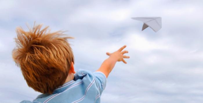 Negative Emissions - Child throwing paper airplane, outdoors, rear view.jpg