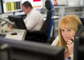 National Grid representative on the phone in front of computer screens with a similar scene out of focus in the background 